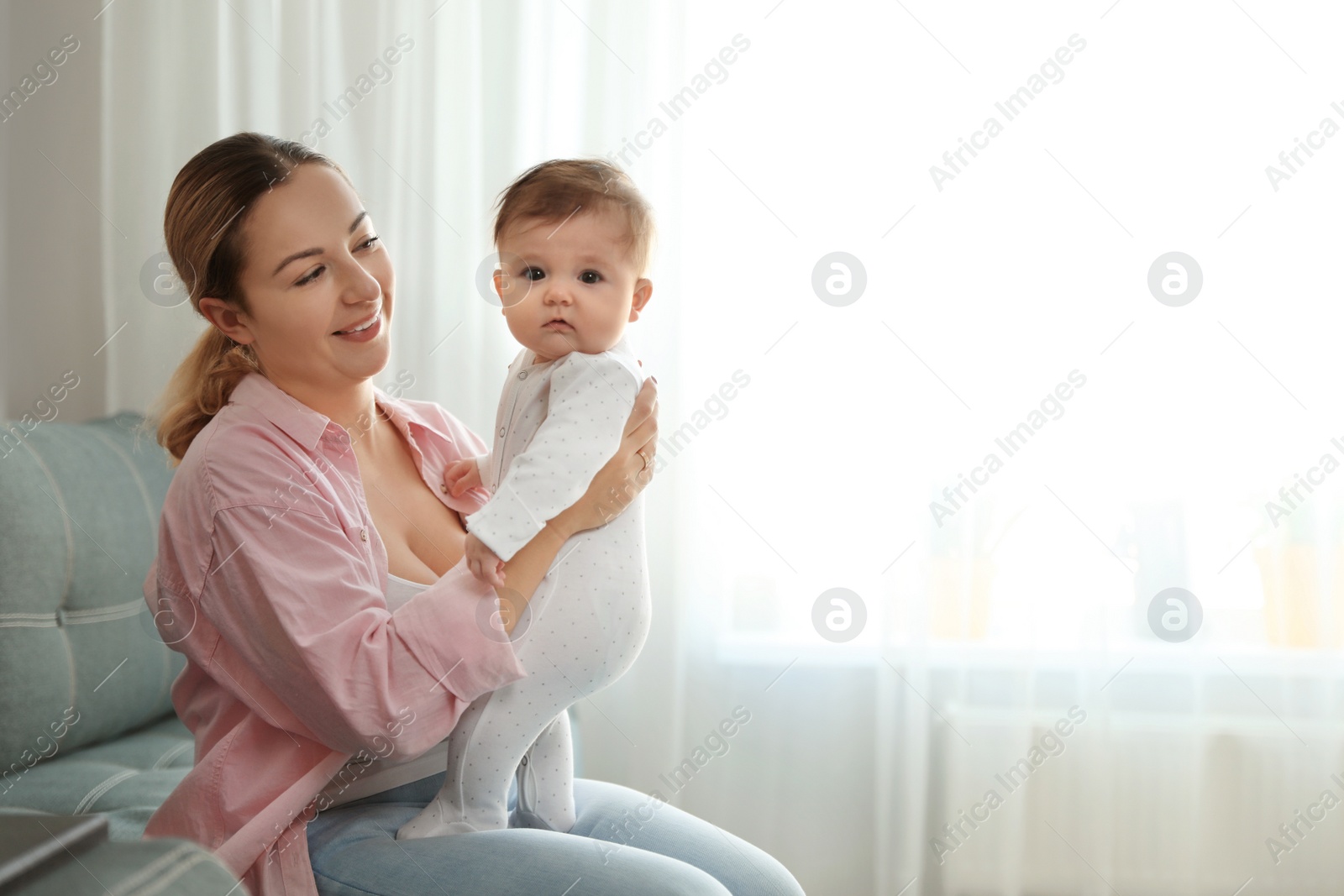 Photo of Young woman with her cute baby at home. Space for text