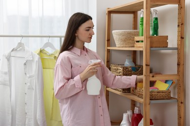 Beautiful young woman with detergent in laundry room