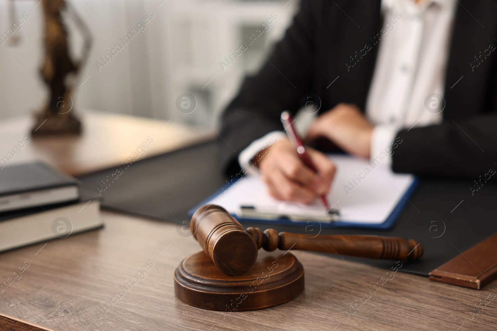 Photo of Notary with clipboard writing notes at workplace in office, focus on mallet