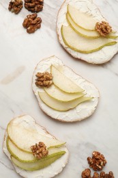 Photo of Delicious bruschettas with ricotta cheese, pears and walnuts on light marble table, flat lay