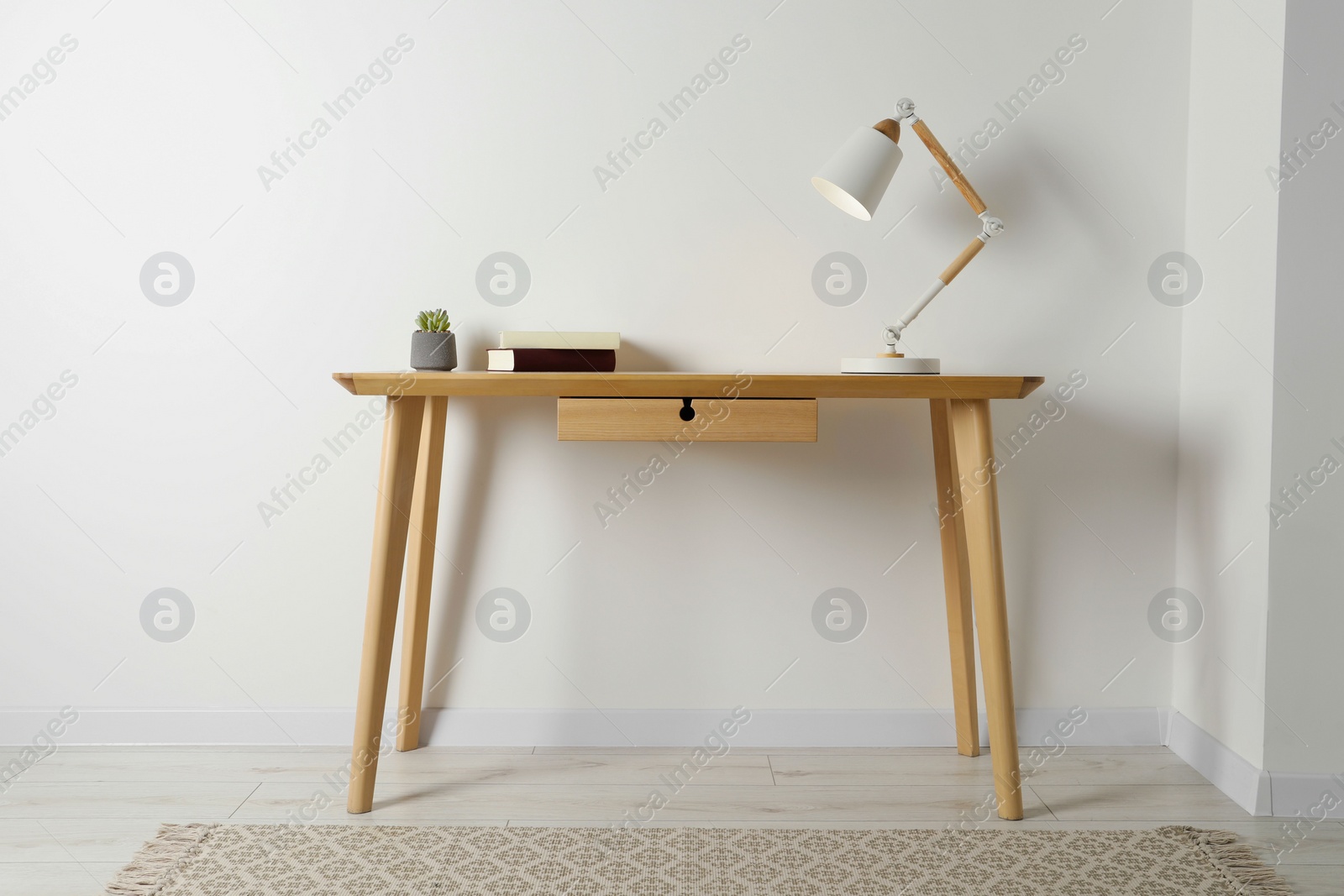 Photo of Stylish lamp, books and houseplant on wooden table in light room. Interior design