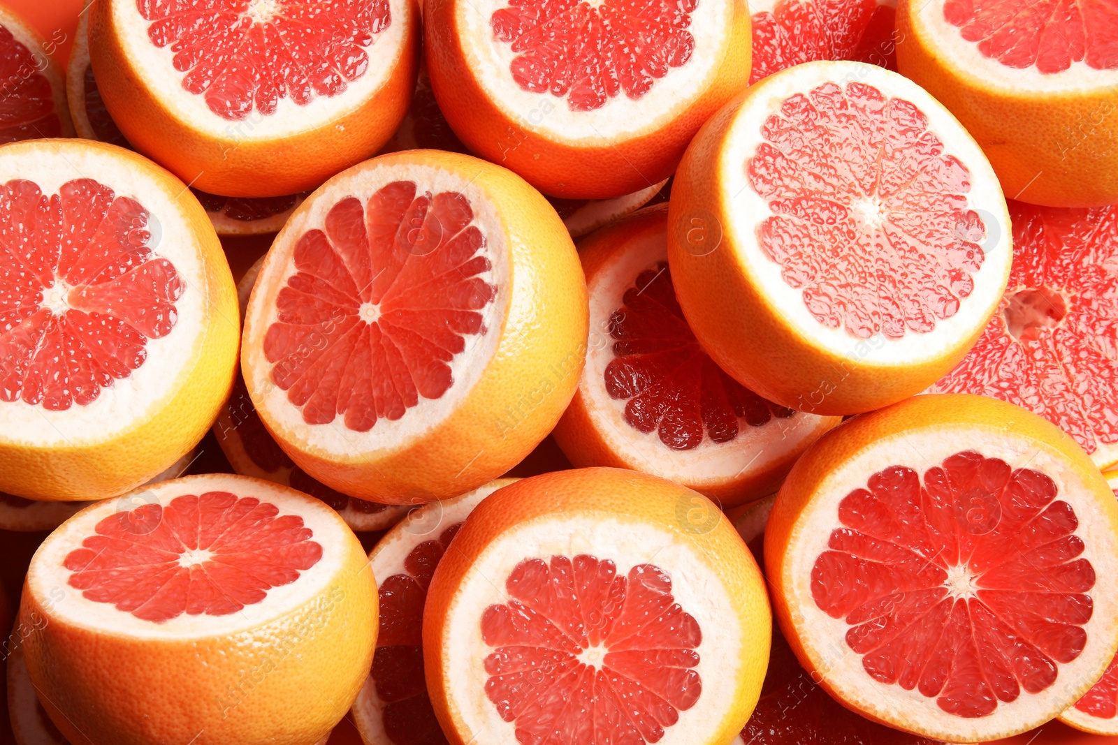 Photo of Many sliced fresh grapefruits as background, top view