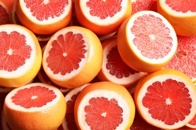 Many sliced fresh grapefruits as background, top view