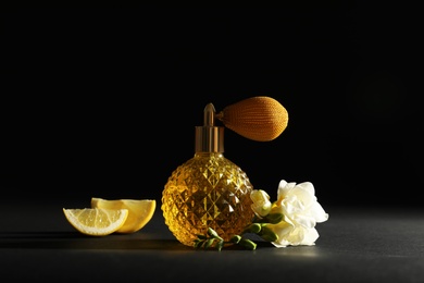 Photo of Vintage bottle of perfume, beautiful flower and citrus fruit on black background