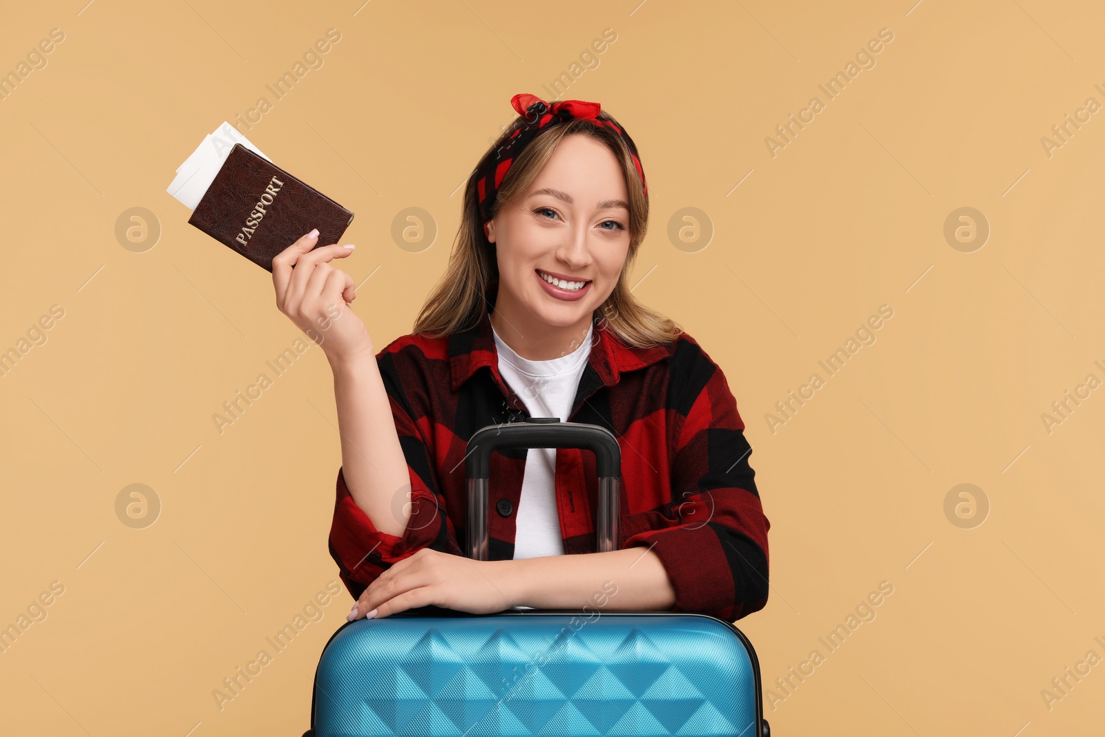 Photo of Happy young woman with passport, ticket and suitcase on beige background