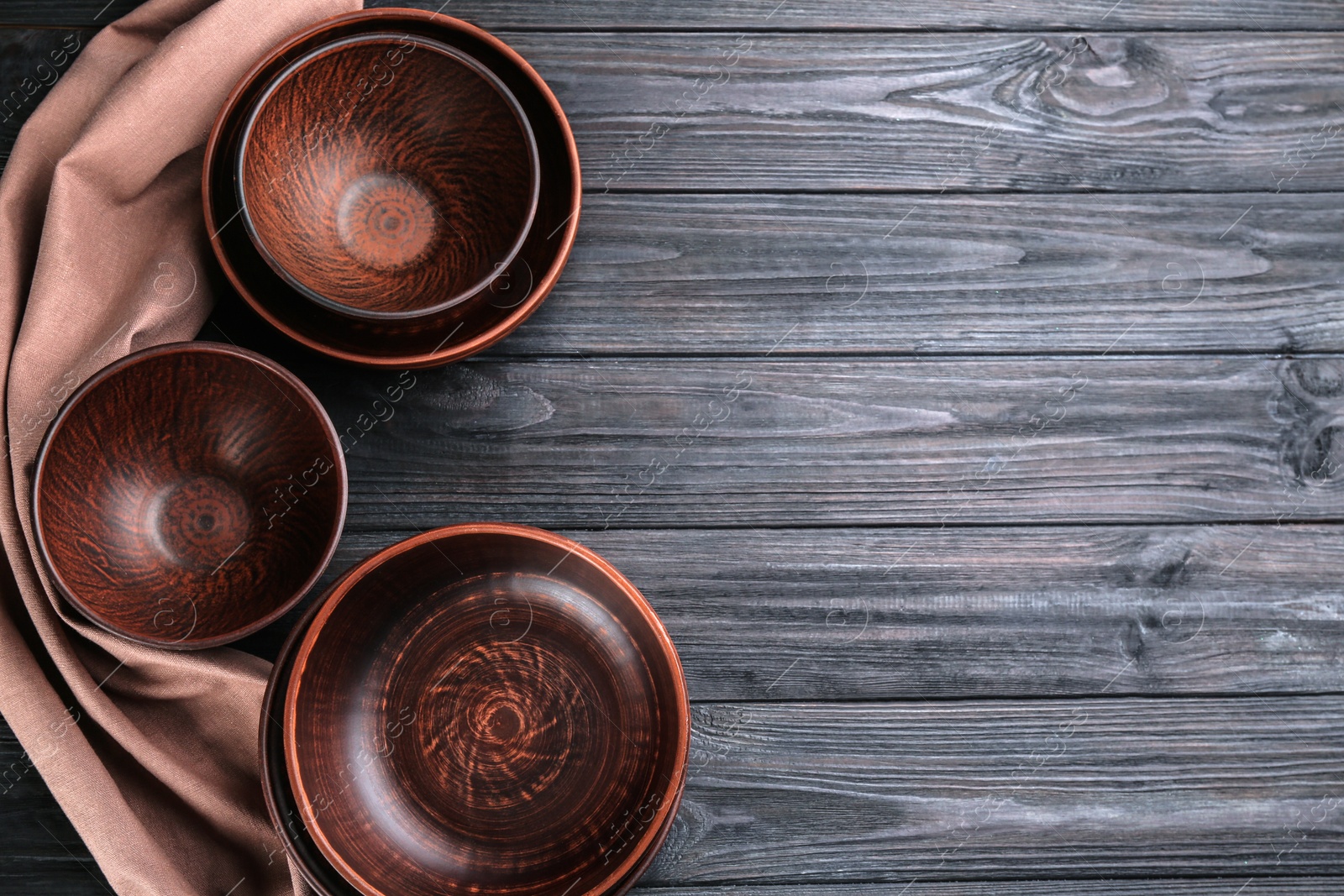 Photo of Clay bowls on black wooden table, flat lay with space for text. Handmade utensils