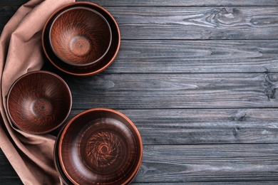 Photo of Clay bowls on black wooden table, flat lay with space for text. Handmade utensils