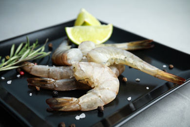 Photo of Fresh raw shrimps with lime and rosemary on plate, closeup