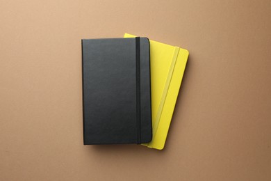 Different notebooks on light brown background, top view