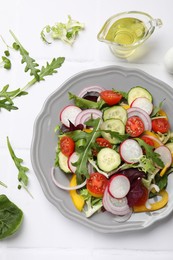 Balanced diet and vegetarian foods. Plate with different delicious products on white tiled table, flat lay