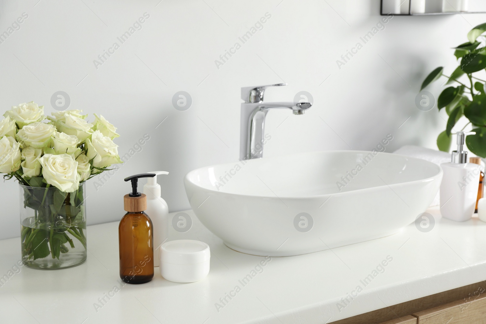 Photo of Beautiful roses and bath accessories near sink in bathroom