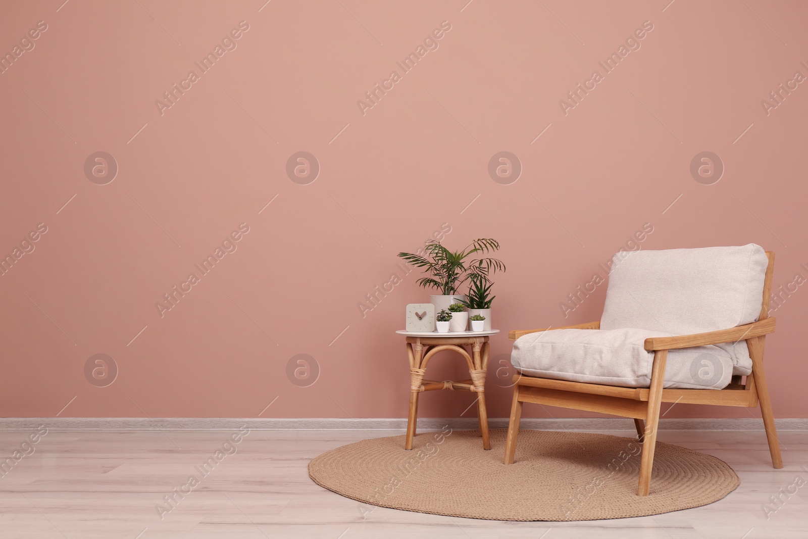 Photo of Stylish room interior with armchair and green plants near pale pink wall, space for text