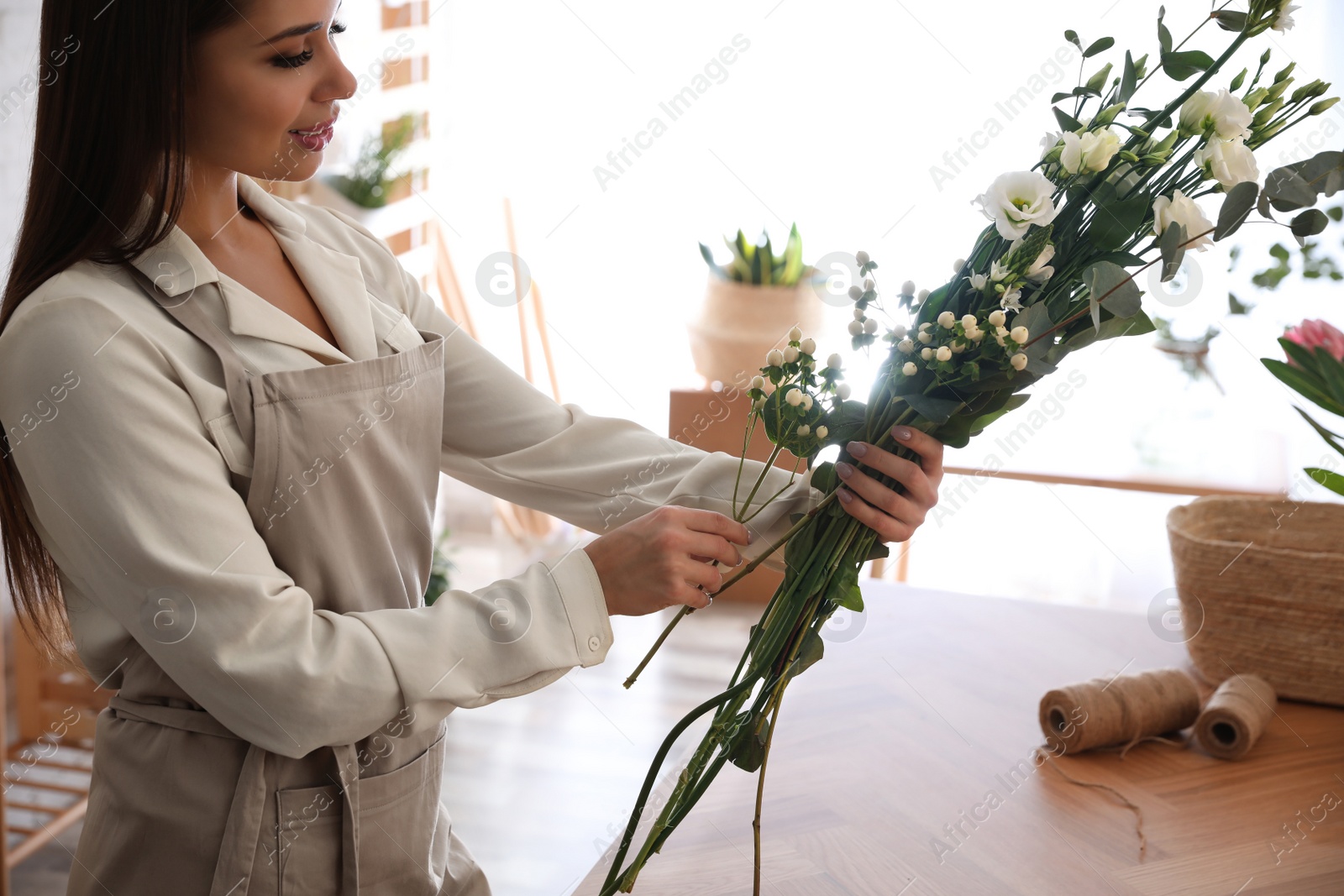 Photo of Florist making beautiful bouquet at table in workshop