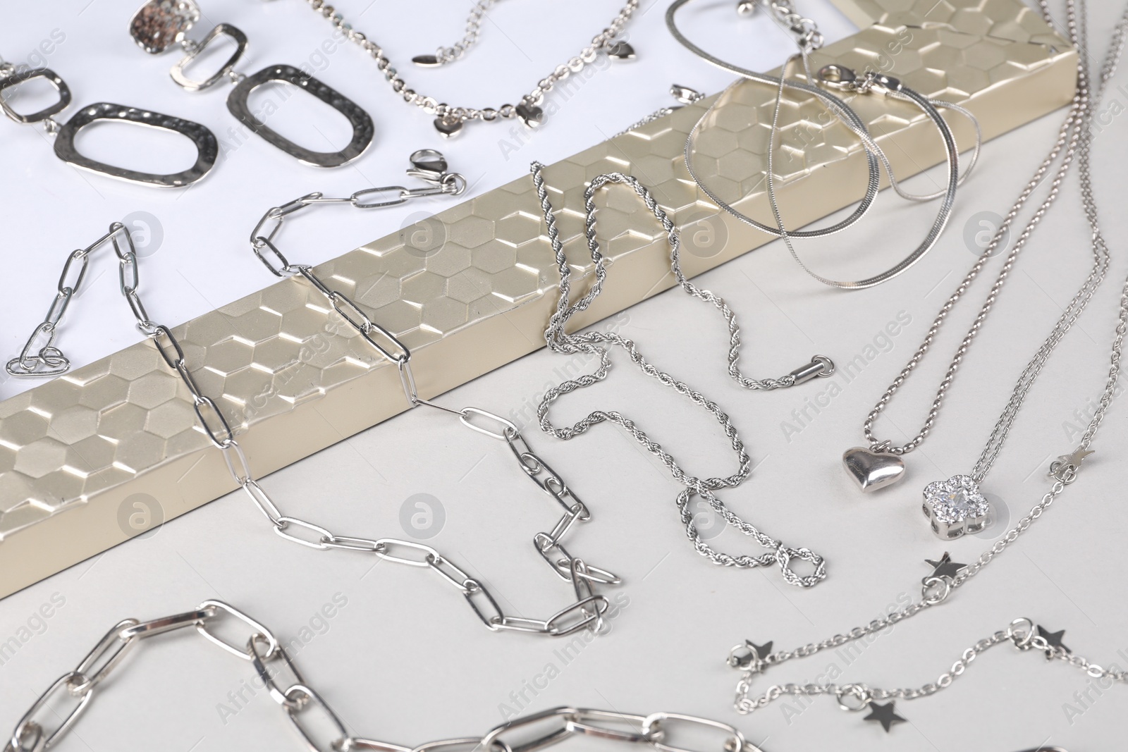 Photo of Metal chains and other different accessories on light table. Luxury jewelry