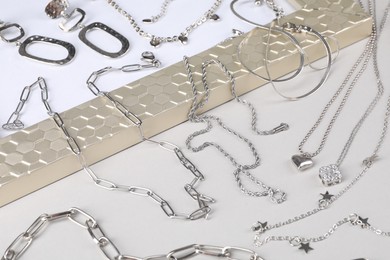 Photo of Metal chains and other different accessories on light table. Luxury jewelry