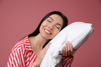 Photo of Beautiful Asian woman with pillow on dusty rose background. Bedtime