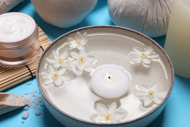 Photo of Beautiful composition with spa products, burning candle and flowers on light blue background