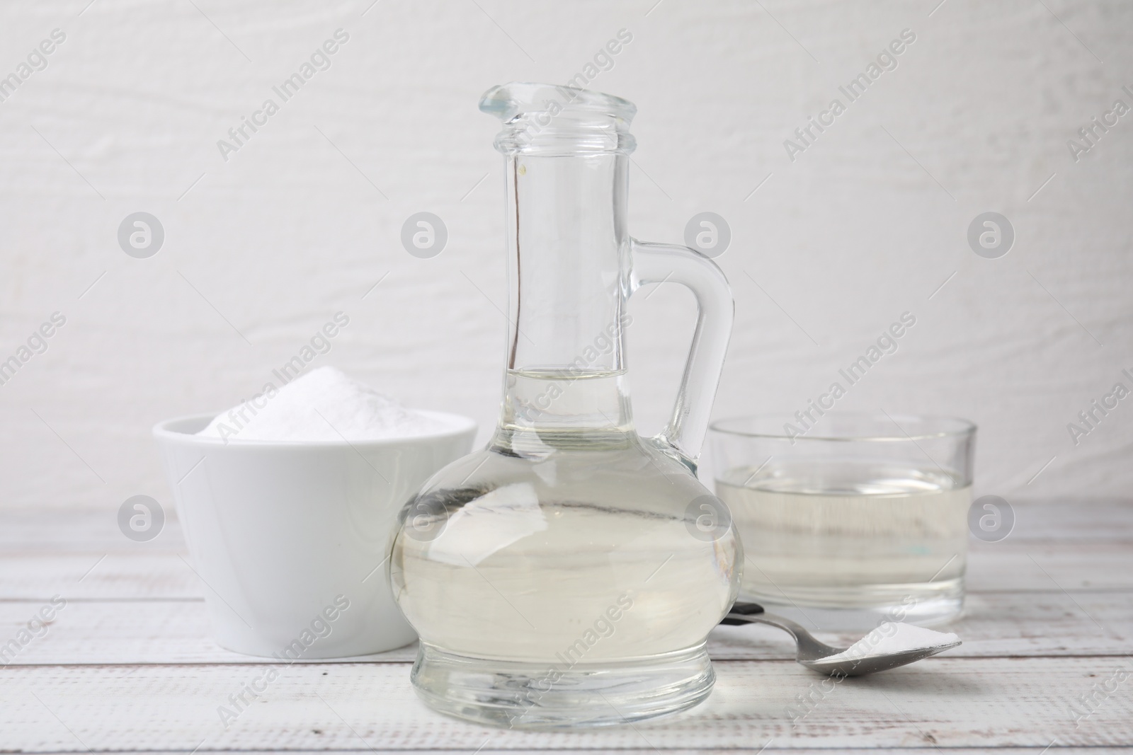 Photo of Vinegar and baking soda on white wooden table