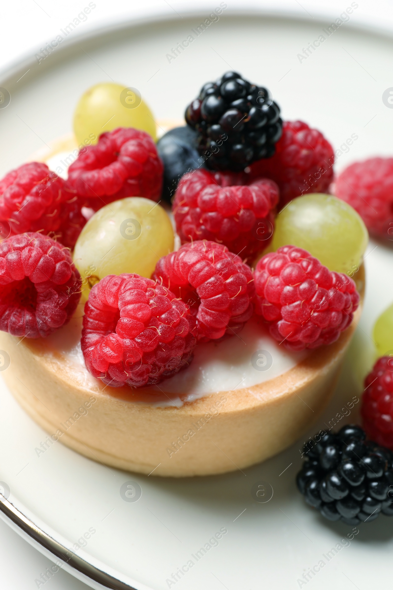 Photo of Delicious tartlet with berries on plate, closeup