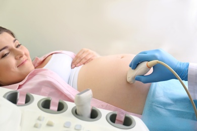 Photo of Young pregnant woman undergoing ultrasound scan in clinic