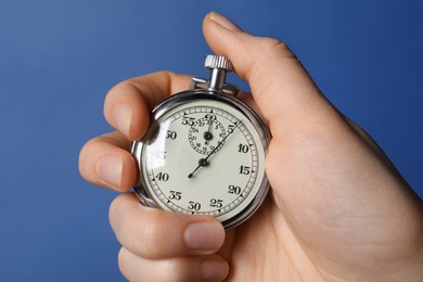 Photo of Woman holding vintage timer on blue background, closeup