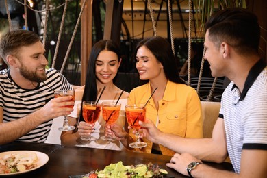 Photo of Friends with Aperol spritz cocktails resting together at restaurant