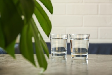 Photo of Glasses of water on grey table indoors