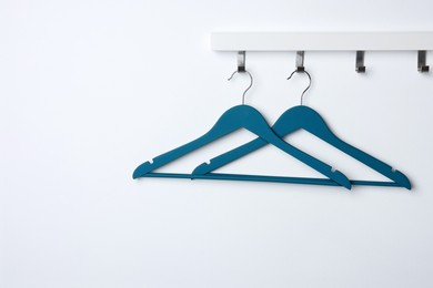 Photo of Rack with empty blue clothes hangers on white wall