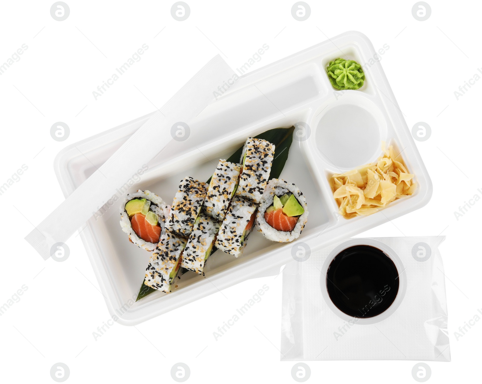 Photo of Food delivery. Plastic container with delicious sushi rolls and bowl of soy sauce on white background, top view