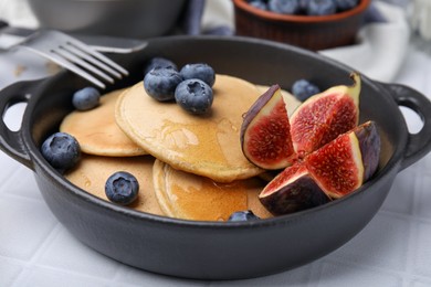 Photo of Tasty oatmeal pancakes on white tiled table, closeup