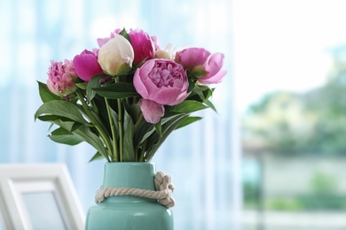 Photo of Vase with bouquet of beautiful peonies in room, space for text