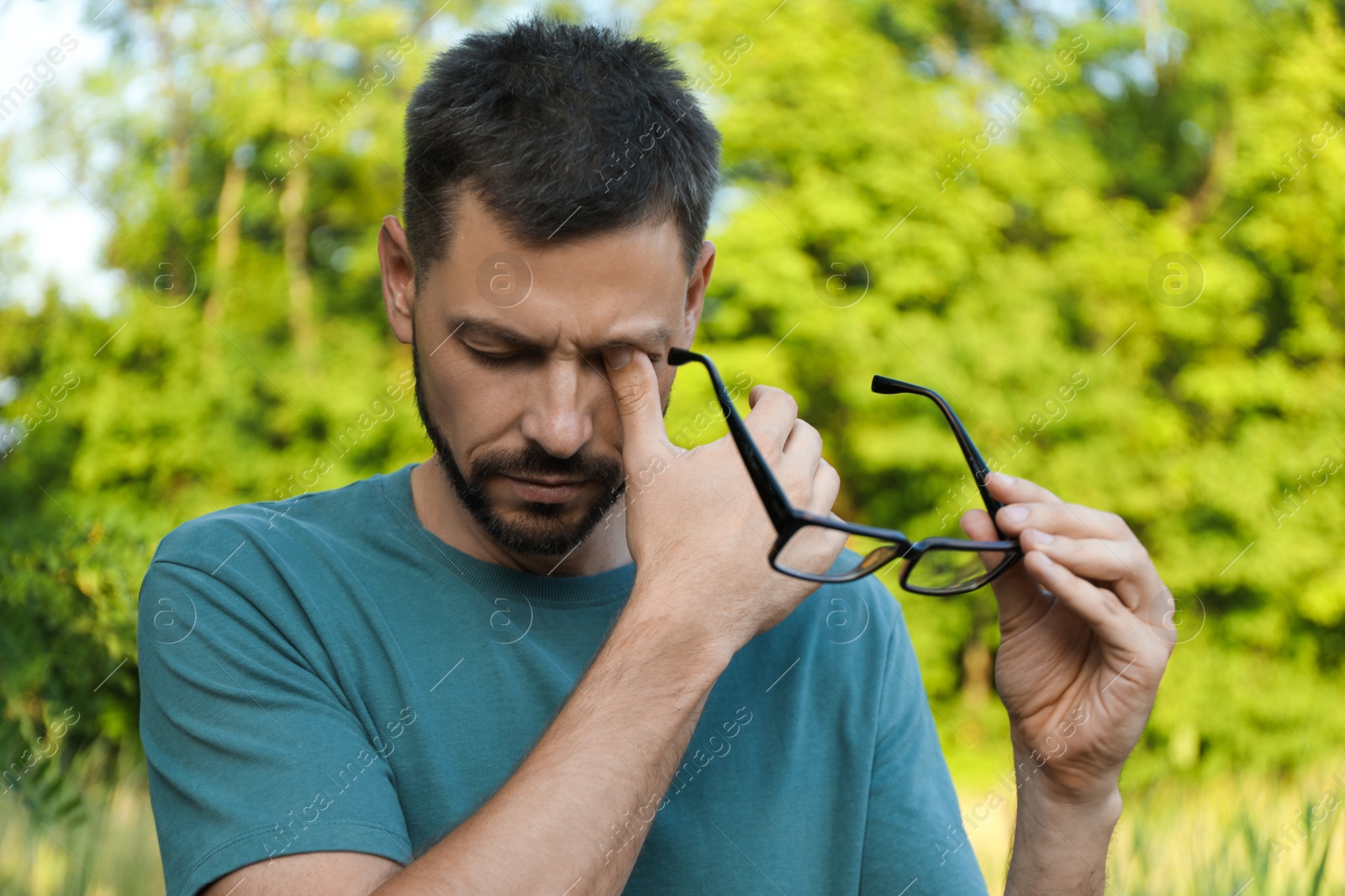 Photo of Man suffering from eyestrain outdoors on sunny day