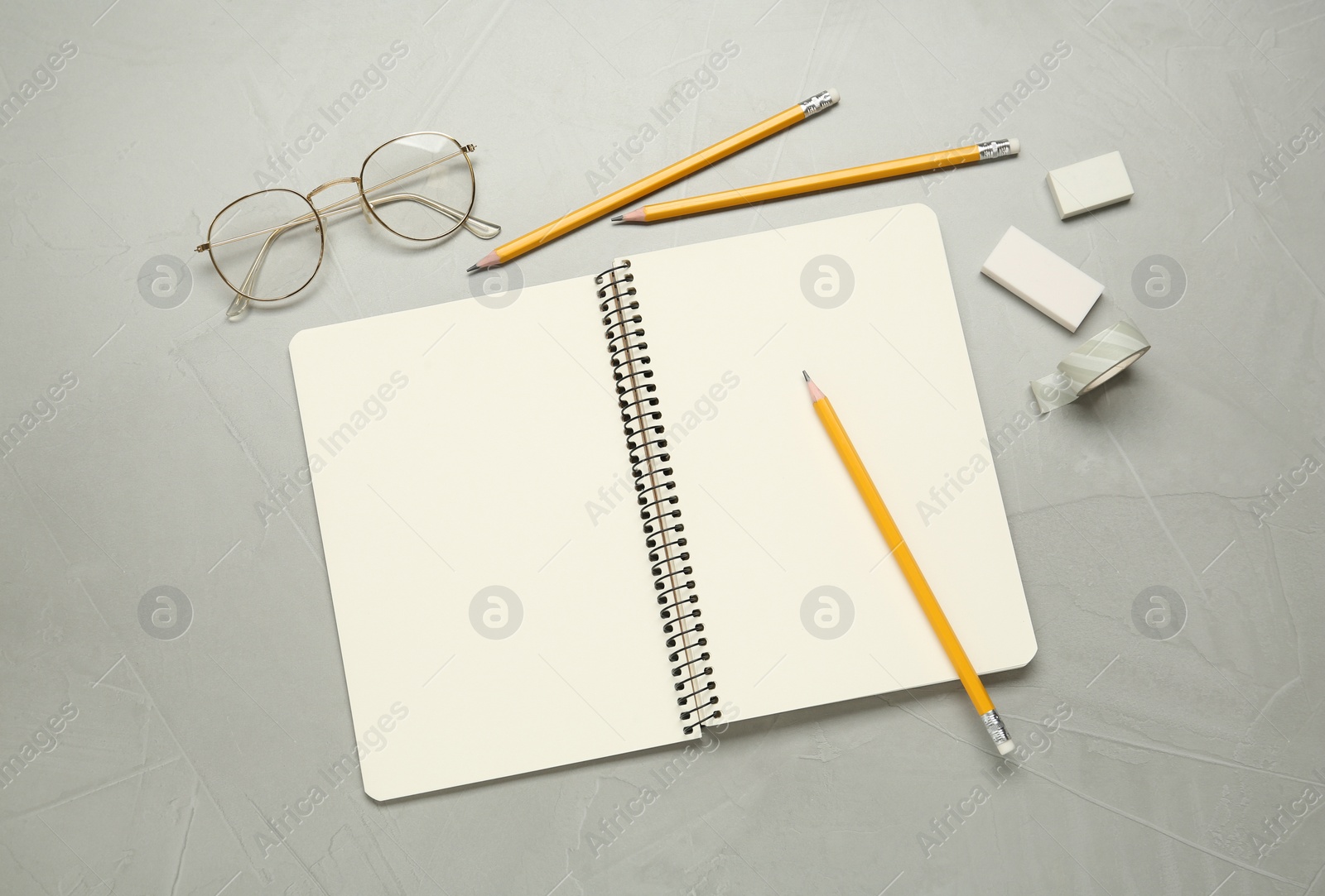 Photo of Flat lay composition with sketchbook, glasses and stationary on light grey table