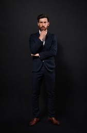 Photo of Handsome bearded man in suit on black background