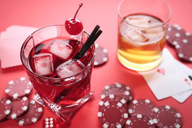 Photo of Casino chips, dice, playing cards and alcohol drinks on red table, closeup