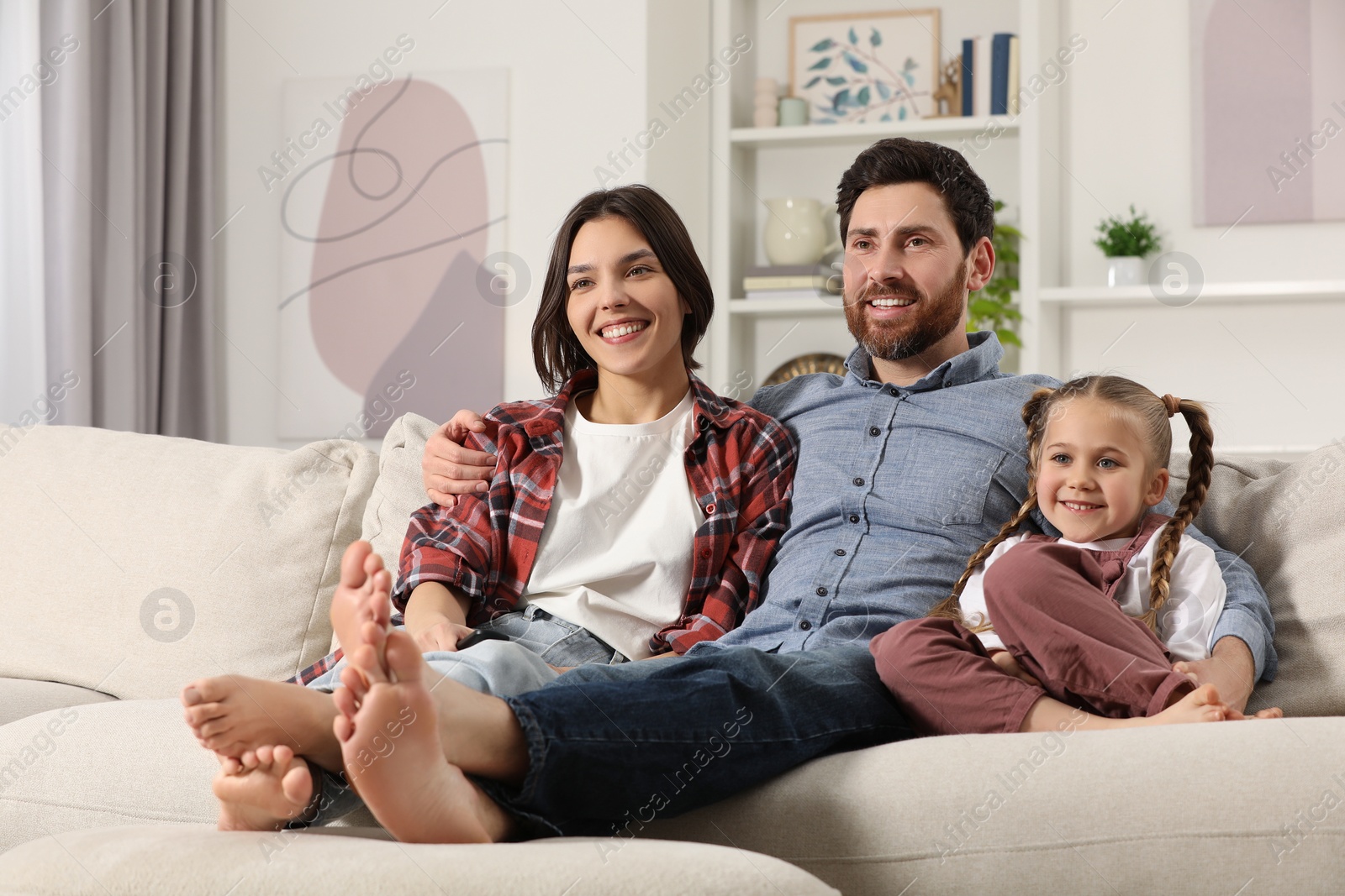 Photo of Happy family watching TV on sofa at home