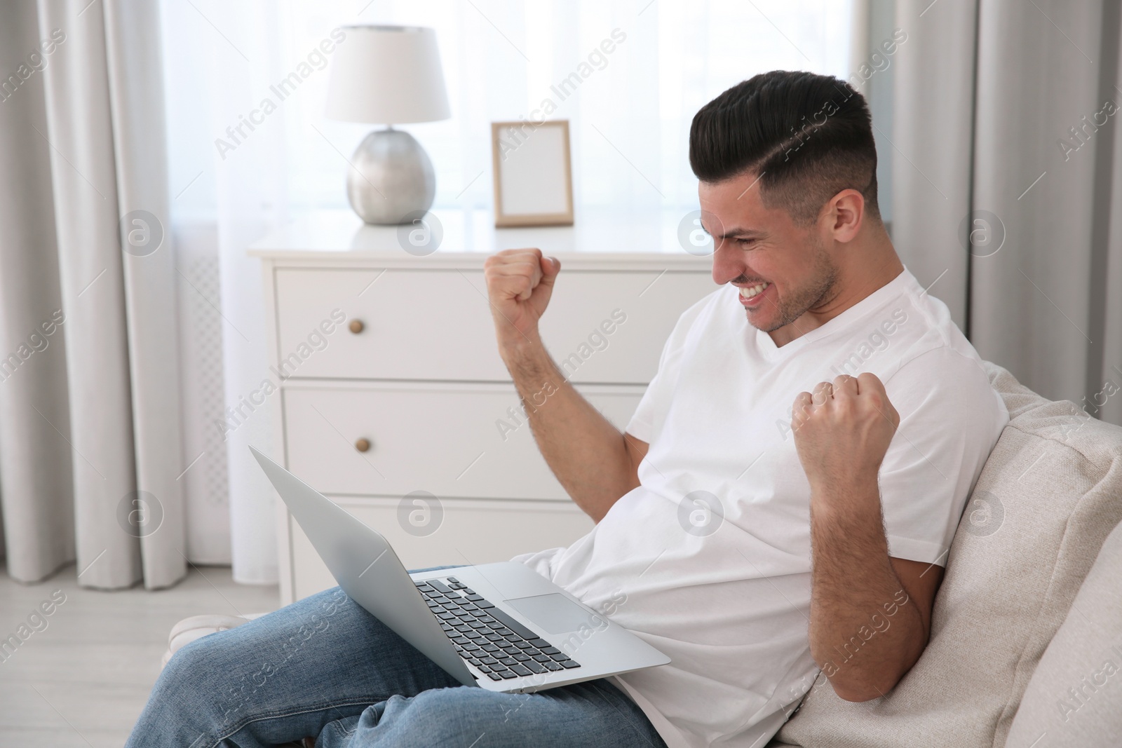 Photo of Emotional man participating in online auction using laptop at home