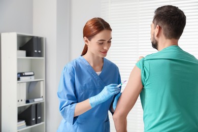 Doctor giving hepatitis vaccine to patient in clinic