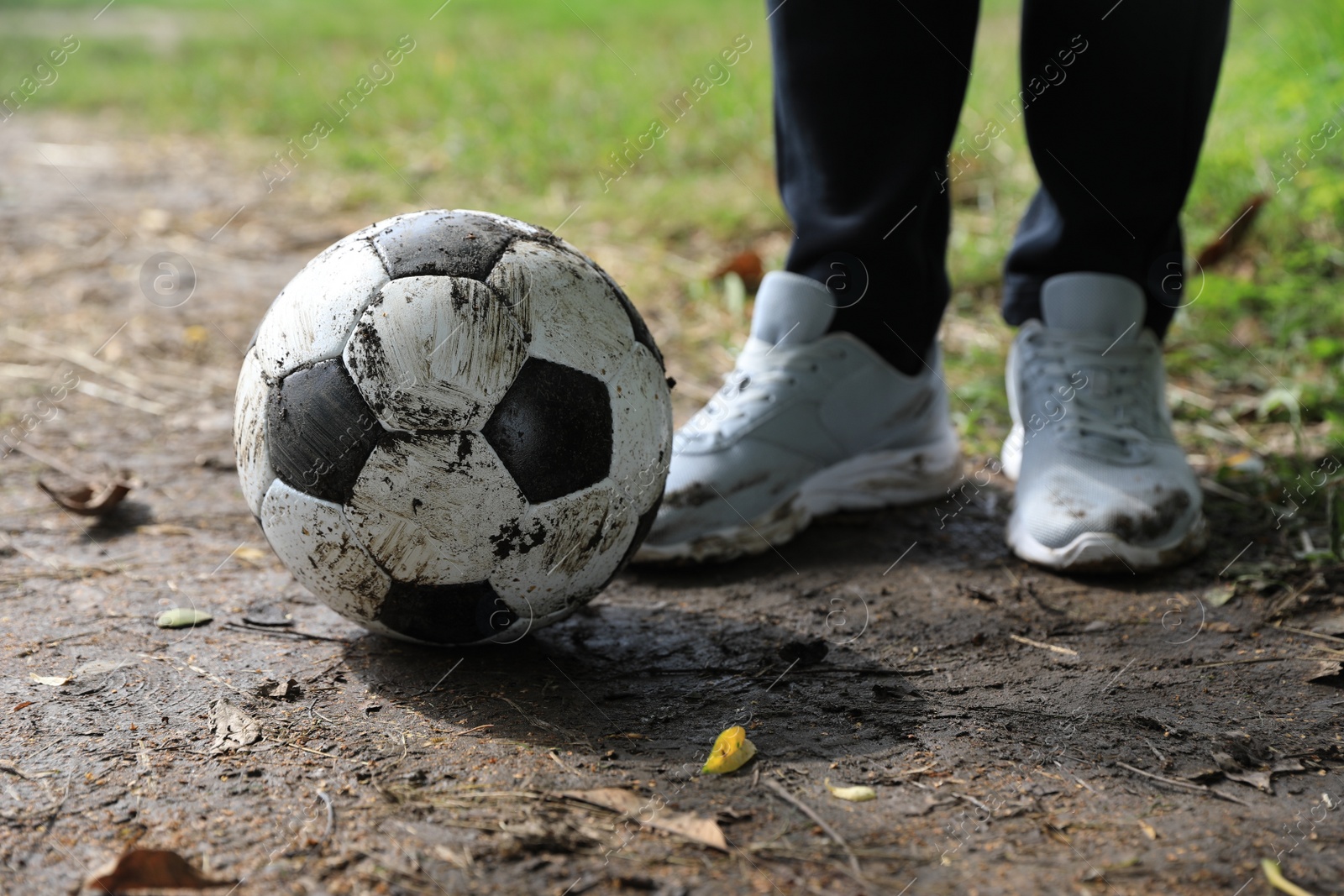 Photo of Man with dirty soccer ball outdoors, closeup