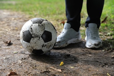 Man with dirty soccer ball outdoors, closeup