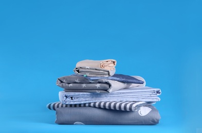 Photo of Stack of clean bed sheets on blue background