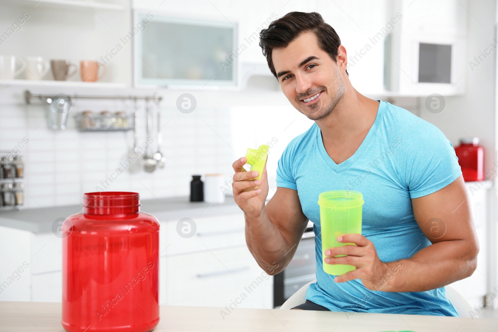 Photo of Young athletic man preparing protein shake in kitchen