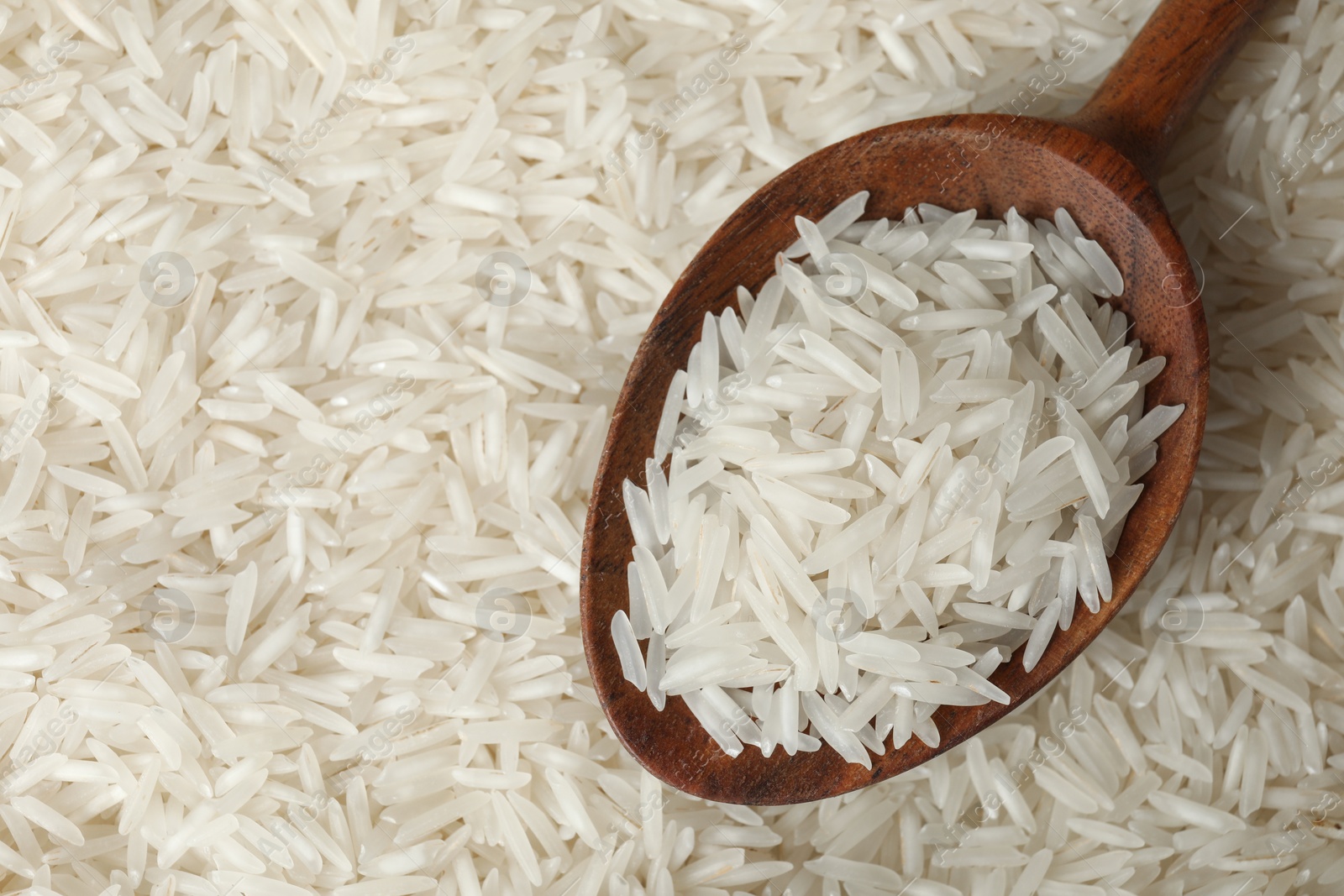 Photo of Raw basmati rice and spoon as background, top view. Space for text