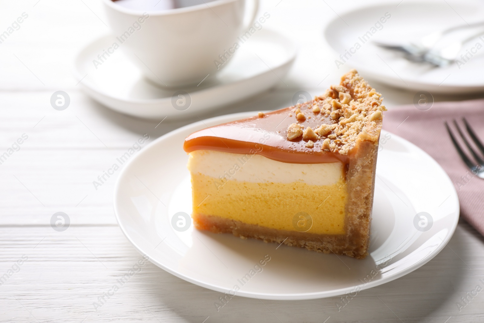 Photo of Piece of delicious cake with caramel served on white wooden table