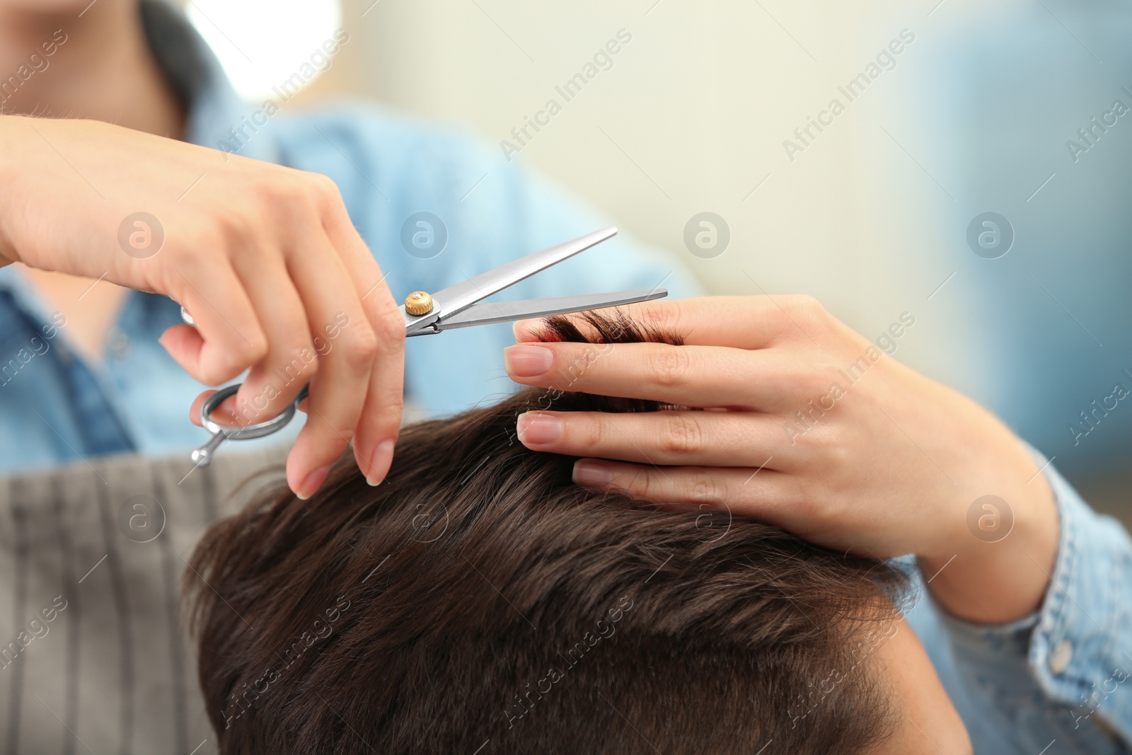 Photo of Barber making stylish haircut with professional scissors in beauty salon, closeup