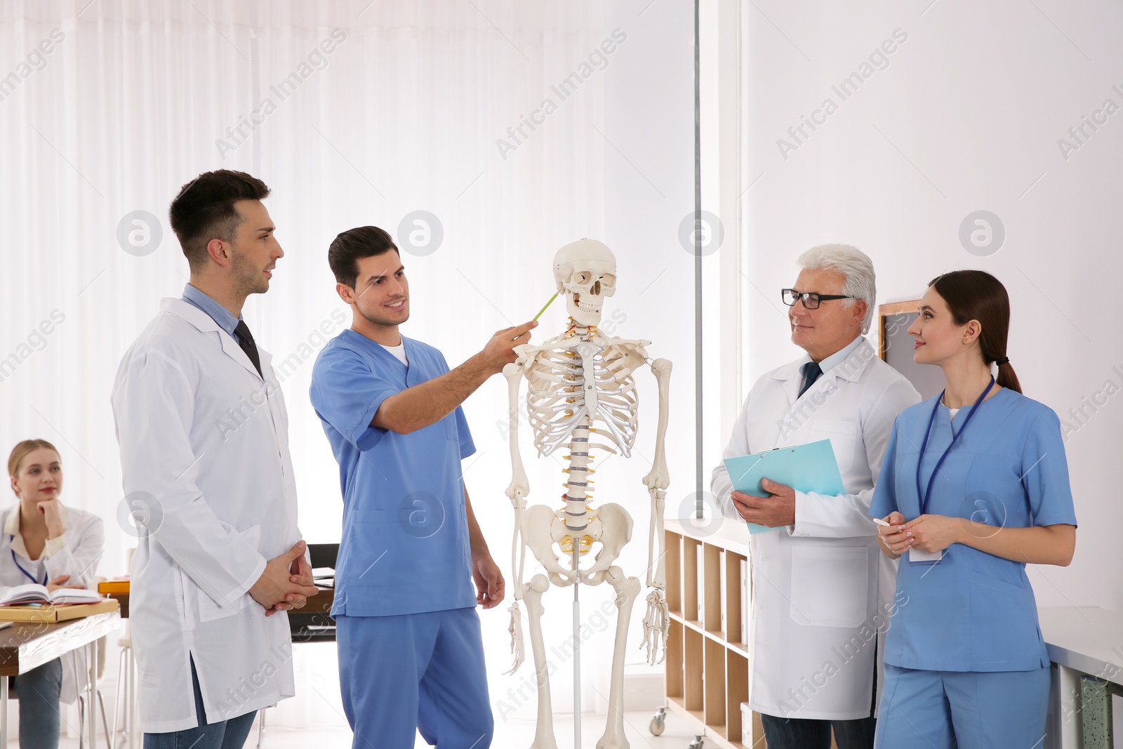 Photo of Medical students and professor studying human skeleton anatomy in classroom