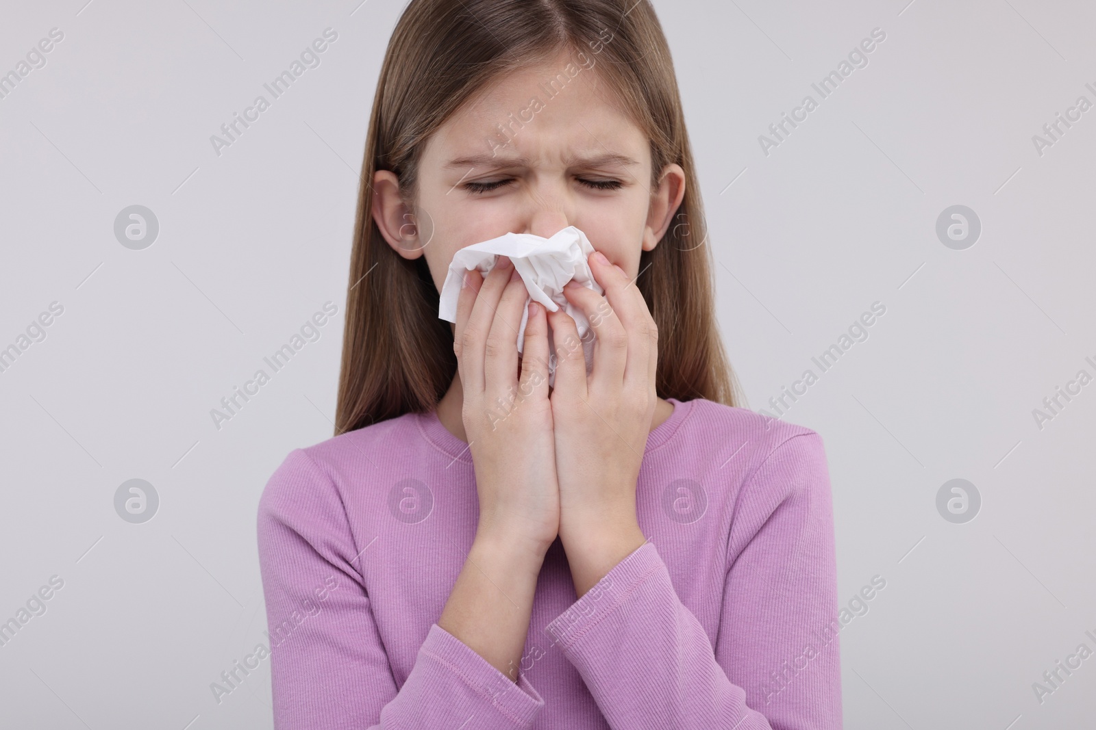 Photo of Sick girl with tissue coughing on light background