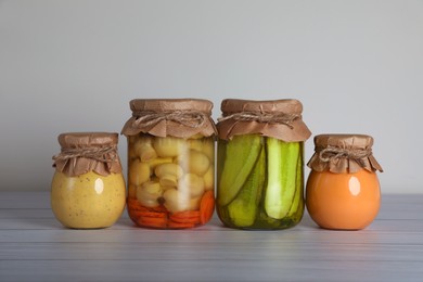 Jars with different preserved ingredients on wooden table