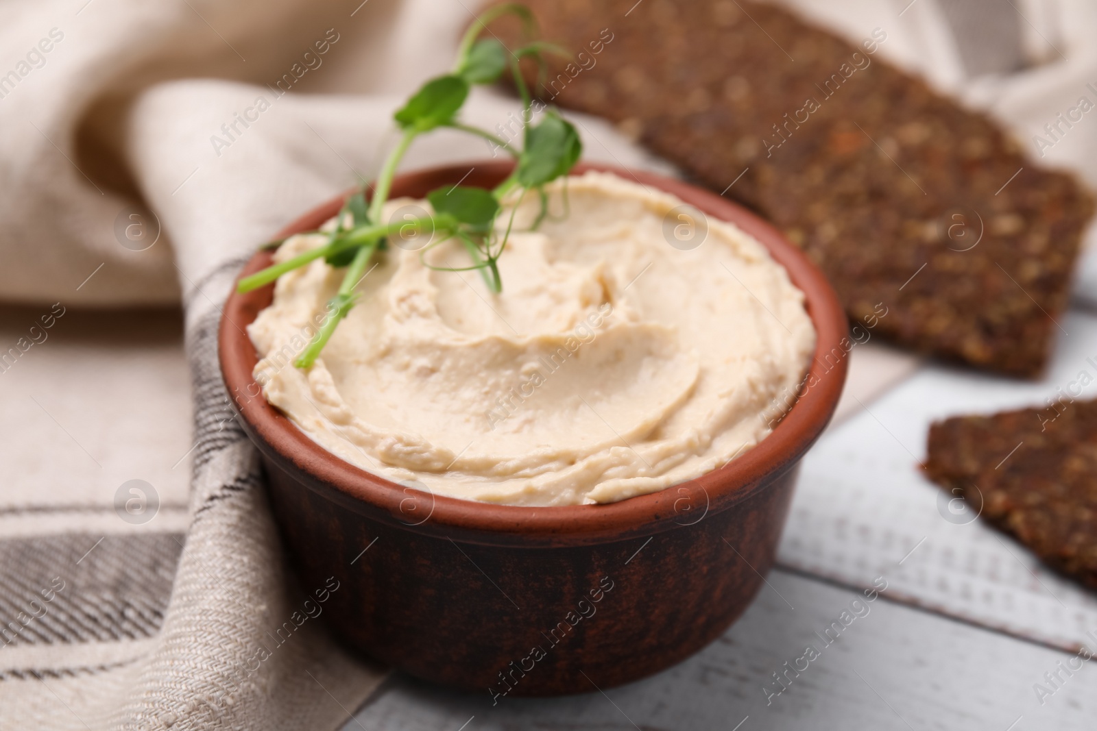 Photo of Delicious hummus served on white wooden table, closeup