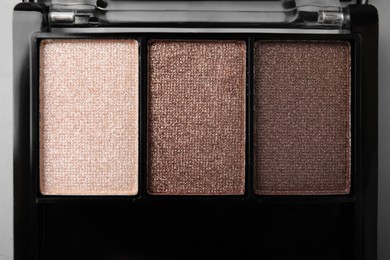 Photo of Beautiful eyeshadow palette on light gray background, closeup. Professional cosmetic product
